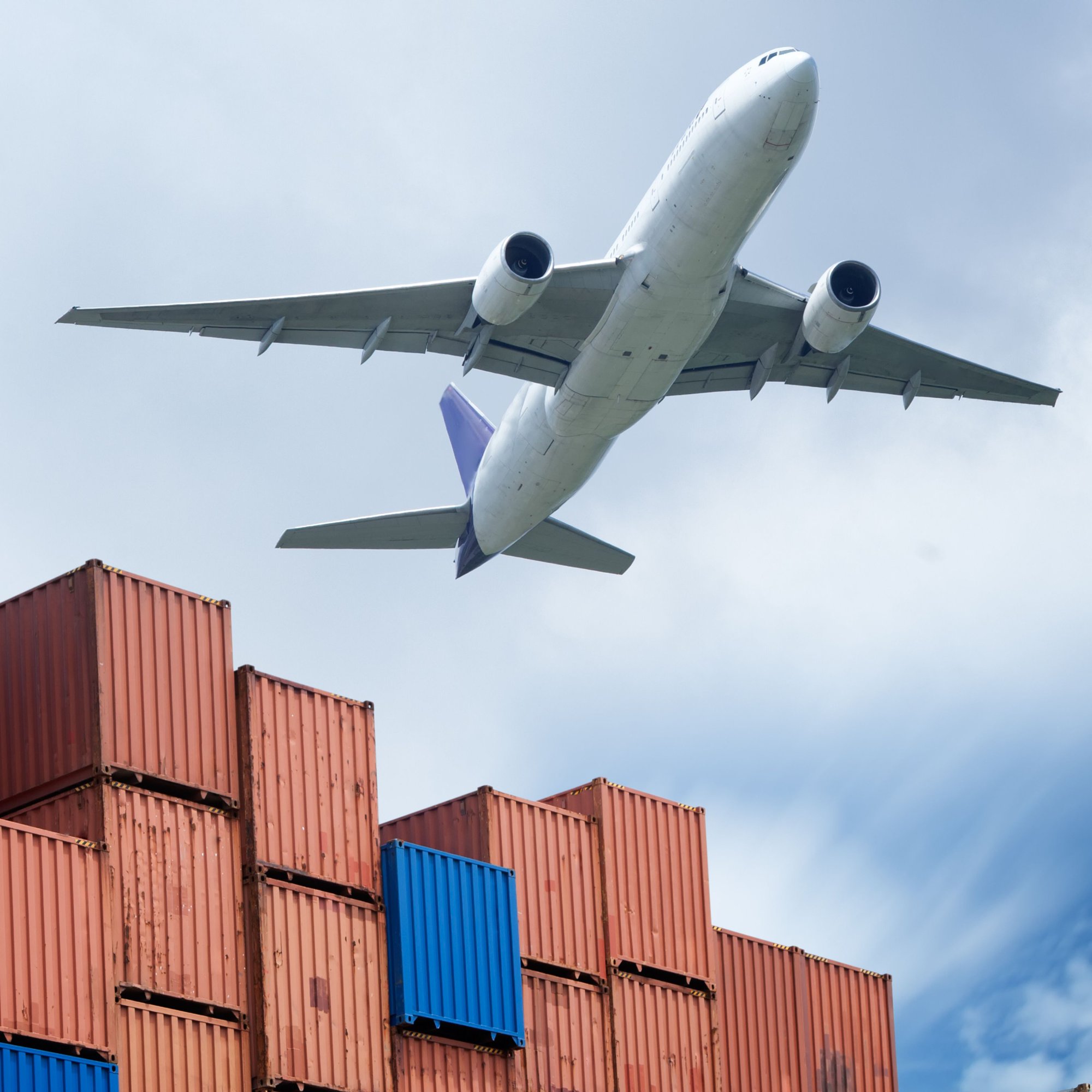 Plane flying out of an industrial port.