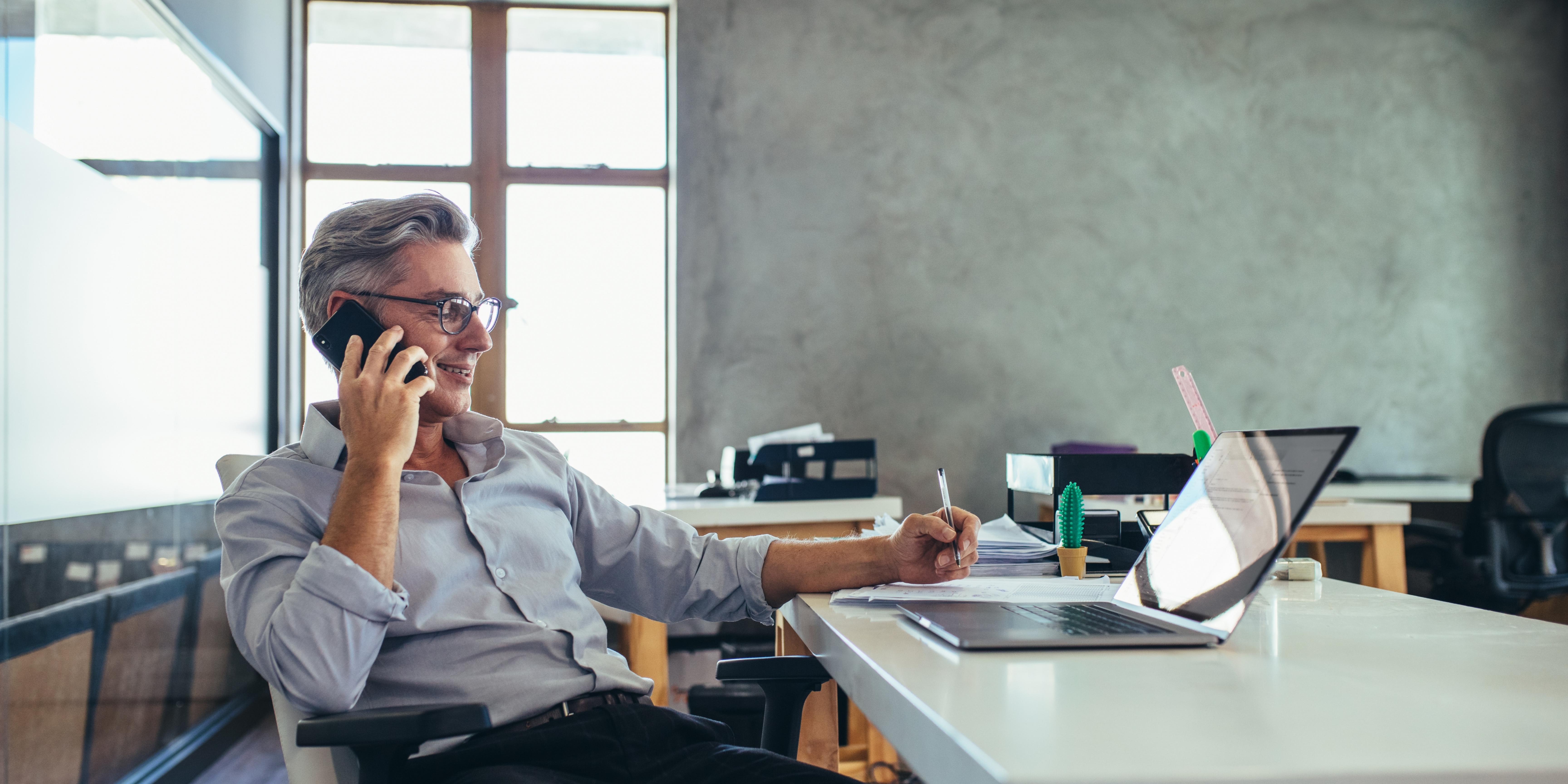 A man talking on the phone in his office. 