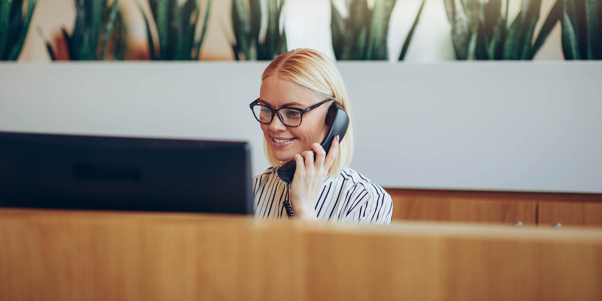 Une femme qui parle au téléphone et regarde son ordinateur.